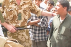 In Az Zubayr, Iraq, Col. Bruce Duncan, commander of the Duke of Wellington's Regiment, teaches a group of school children, on their first day back to school that the bayonet this boy was carrying is dangerous and that they will not carry weapons to school anymore. (Photo by Capt. Deborah Molnar, commander, 19th Public Affairs Detachment). 030419-A-6090M-001